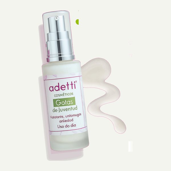 Frasco con dosificador de Gotas de Juventud Adetti junto a una textura de crema